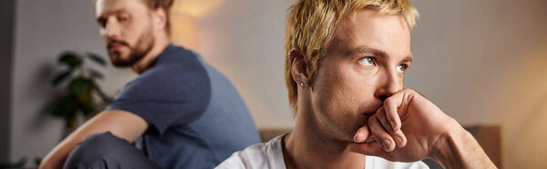 обиженный гей держит руку возле лица и смотрит в сторону рядом с парнем в спальне, баннер