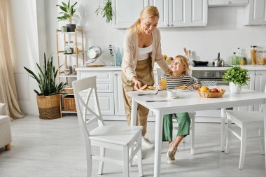 Mutfakta kahvaltıda protez bacaklı kızına krep servis eden mutlu bir anne.