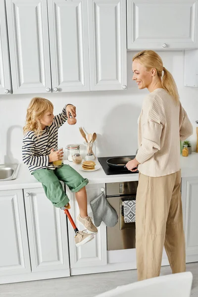 Protez bacaklı küçük bir kız elinde tarçınlı cam kavanoz ve portakal suyu olan mutlu bir anne.
