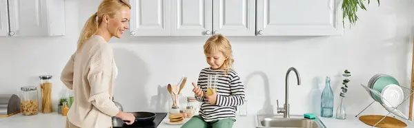 Chica Feliz Sentado Encimera Celebración Jugo Naranja Cerca Madre Cocinar — Foto de Stock