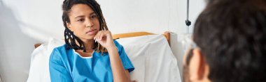 Çekici, hasta, afro-amerikan kadın hastane yatağında yatarken Hintli genç doktor ve afişleri dinliyor.