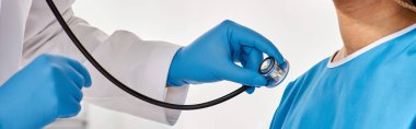 Hintli doktor, steteskoplu, kırpılmış, afişi olan hasta Afrikalı Amerikalı hastasının nefesini dinliyor.