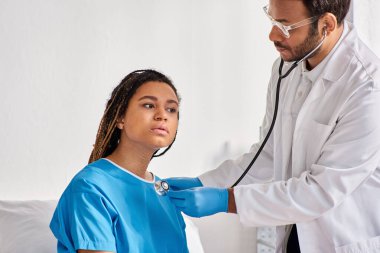 Hintli doktor, hastane koğuşundaki Afro-Amerikan kadın hastasının nefesini kontrol ediyor.