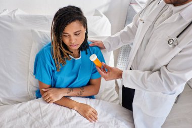 Hintli doktorun depresyondaki Afrikalı Amerikalı hastasına haplar verirken çekilmiş görüntüsü.
