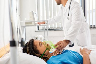 young indian doctor helping his sick african american female patient with oxygen mask, healthcare clipart