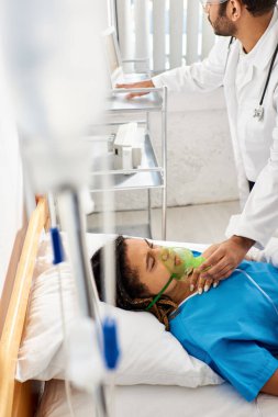 Genç Hintli doktor, hasta Afrikalı Amerikalı kadın hastasına oksijen maskeli, sağlık hizmetlerinde yardım ediyor.