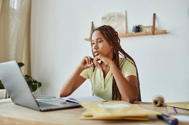 good looking african american female merchant looking at her laptop attentively, delivery concept clipart