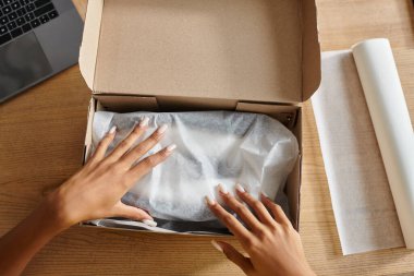 cropped view of young african american female seller packing box before sending, delivery concept clipart