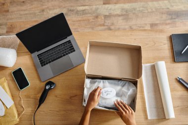 Sıkı çalışan Afro-Amerikan kadın perakendecinin laptopun yanındaki paketleme kutusu, teslimat...