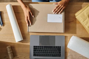 cropped view of african american female merchant with hands on post packet, delivery concept clipart