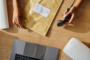 cropped view of young african american woman preparing to scan post packets during work, delivery clipart