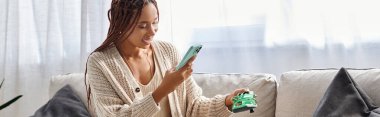 beautiful joyous african american woman with braces taking photo of her new green shoes, banner clipart