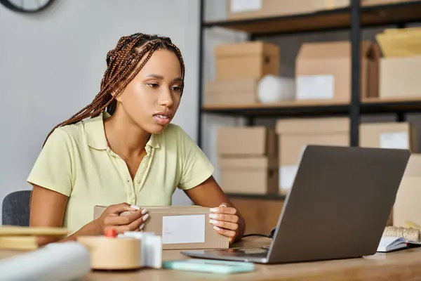 attractive african american female merchant looking at her laptop while working hard, delivery