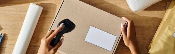 stock image cropped view of ambitious african american female seller scanning box, delivery concept, banner