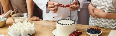 cropped view of chef decorating cake with red currant near diverse students, cooking courses, banner clipart