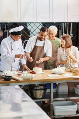 jolly african american man in apron decorating delicious cake next to chef and his friends clipart