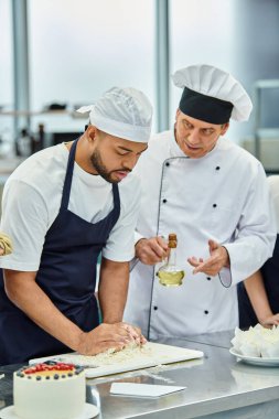 İyi görünümlü Afro-Amerikan şefi Toque ve önlüklü Şef Cook 'un yanında mangır ile çalışıyor.