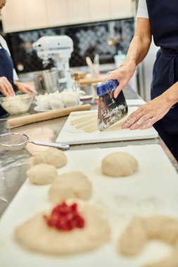 cropped view of mature female chef using cutting board next to her young colleague, confectionery clipart