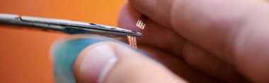 Tamir atölyesi ve afişte elektronik aletin kablosunu kesen deneyimli teknisyenin kısmi görüntüsü