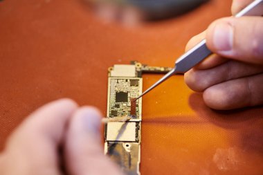 Elektronik mikro çipin yakın görüntüsü özel atölyede çalışan kırpılmış teknisyenin yanında.