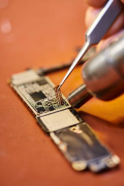 Atölyedeki elektronik aletleri lehimleyen tamirci manzarası, küçük işletmeler.