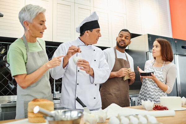 diverse people in casual attires with aprons listening to mature chef attentively, cooking courses
