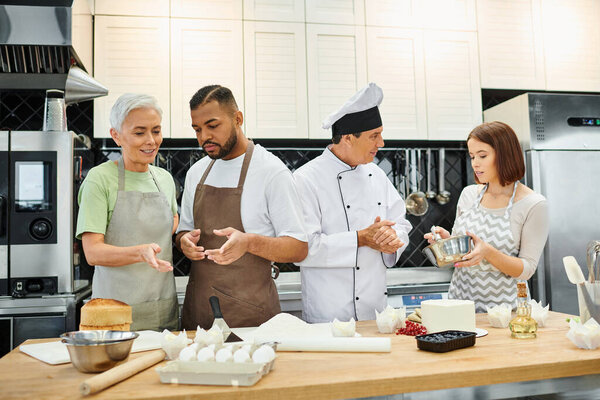 multiracial students in casual attires learning how to bake next to mature chef, cooking courses