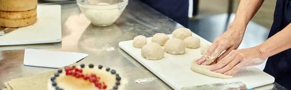 stock image cropped view of mature chef working hard on dough next to her young colleague, confectionery, banner