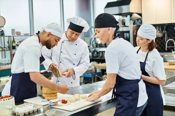 multiracial chefs with their chief cook in white hat baking together on kitchen, confectionary