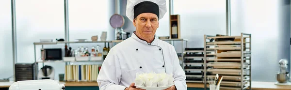 handsome mature chief cook posing on his kitchen and looking at camera, confectionery, banner