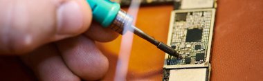 Tamir atölyesinde, yatay pankartta yetenekli teknisyen lehimleme elektronik çip setinin kırpılmış görüntüsü