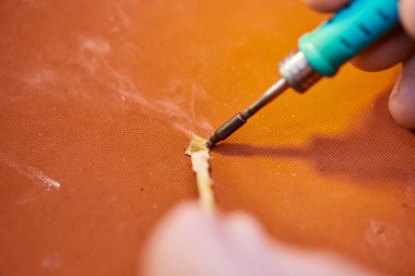 Özel atölyedeki modern elektronik cihazın yetenekli teknisyen lehimleme yongalarının kısmi görüntüsü