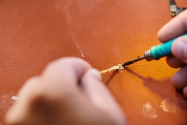 Atölyedeki modern elektronik cihazın lehimlediği yetenekli tamircinin kısmi görüntüsü
