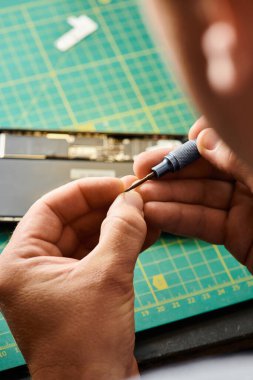 Özel atölyede cep telefonunun yanında elinde tornavida tutan deneyimli bir tamirci görüntüsü