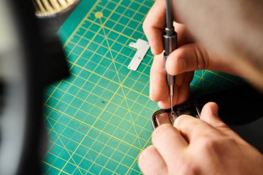 Teknisyenin akıllı telefonu tornavidayla açarken tanılama yaparken görüntüsü kesilmiş.