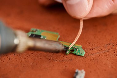 Atölyedeki elektronik çip setinin teknisyen lehimleme görüntüsünü kapat, küçük işletme