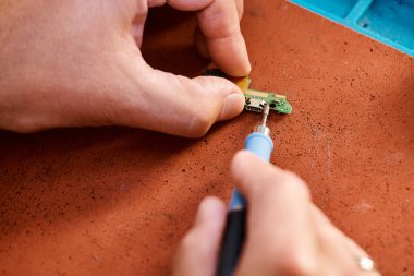 Yetenekli tamircinin atölyede elektronik yedek parça lehimlemesi, bakım işi