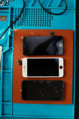 Profesyonel atölyedeki, bakım servisindeki, üst kattaki çalışma masasındaki tamir edilmiş ve kırılmış akıllı telefonlar.