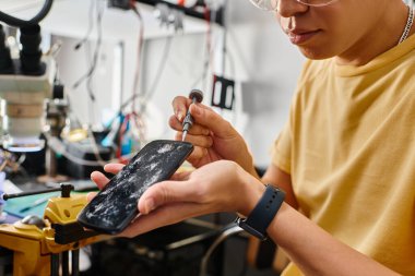 Uzman bir tamircinin bozuk dokunmatik ekranlı akıllı telefonu tornavidayla açarken çekilmiş görüntüsü