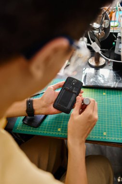 Profesyonel tamircinin bakım atölyesinde bozuk cep telefonunu tamir ederken arka planı