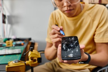 Tornavidalı teknik uzman görüşü ve atölyede dokunmatik ekranı kırık akıllı telefon.