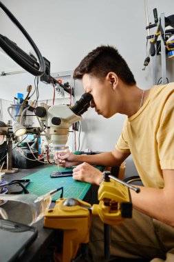 Atölyede mikroskop ve elektronik aletlerle çalışan deneyimli Asyalı tamircinin yan görüntüsü
