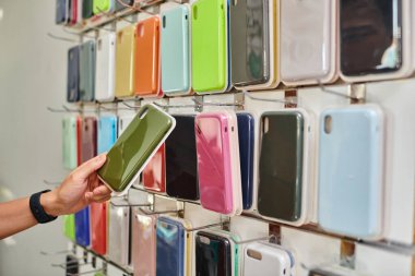 Özel dükkanda çeşitli renkli telefon kılıfları olan vitrinin yanındaki adam manzarası, küçük işletmeler.