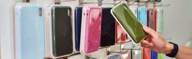 Renkli telefon kılıfları, küçük işletmeler, afişler ile vitrinin yanındaki satıcının kırpılmış görünümü
