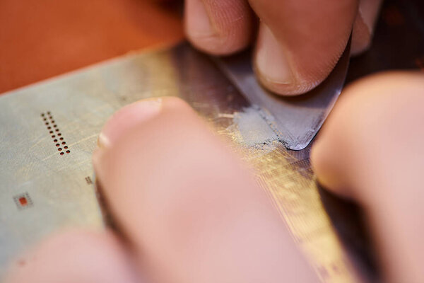 close up view of cropped technician scratching electronic chipset in repair shop, small business