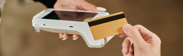 баннер клиента, держащего кредитную карту рядом с кард-ридером, обрезанная рука мужчины, платящего в веганском кафе