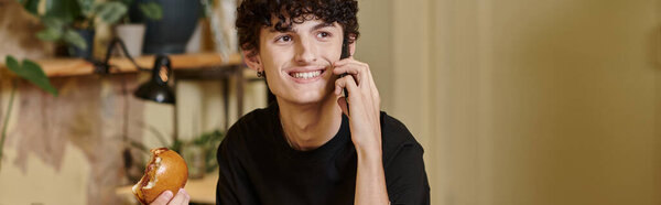 счастливый и молодой человек, держащий тофу-бургер на растительной основе и разговаривающий на смартфоне в веганском кафе, баннер