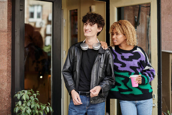 счастливая разнообразная пара в повседневной одежде ходить с растительным напитком на основе у входа в веганское кафе