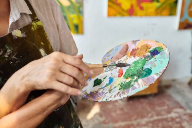 Olgun bir kadın ve yetenekli bir kadın palette boya karıştırıyor. Sanat atölyesinde yüksek lisans yapıyor.
