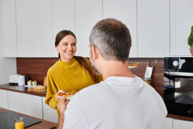 Mutlu eş, modern mutfakta, çocuksuz çifte lezzetli bir kahvaltı hazırlıyor.